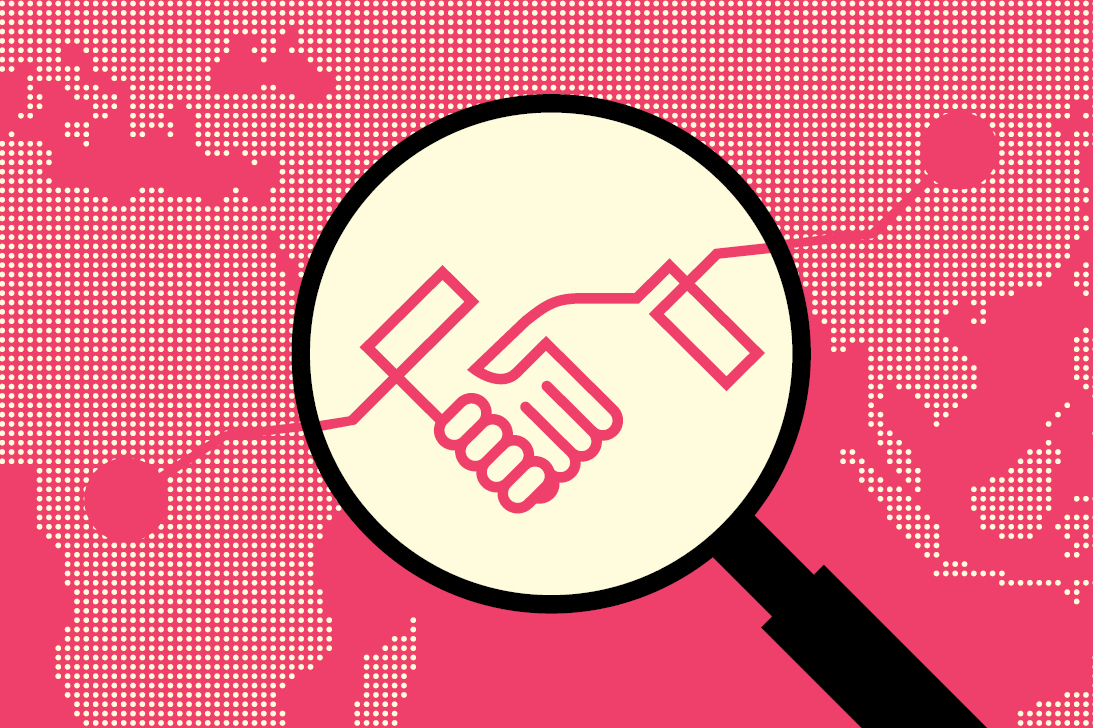 A magnifying glass showing two hands shaking on a pink world map background A magnifying glass showing two hands shaking on a pink world map background