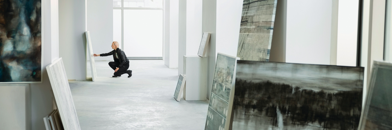 An art gallery with a visitor looking at a painting closely An art gallery with a visitor looking at a painting closely