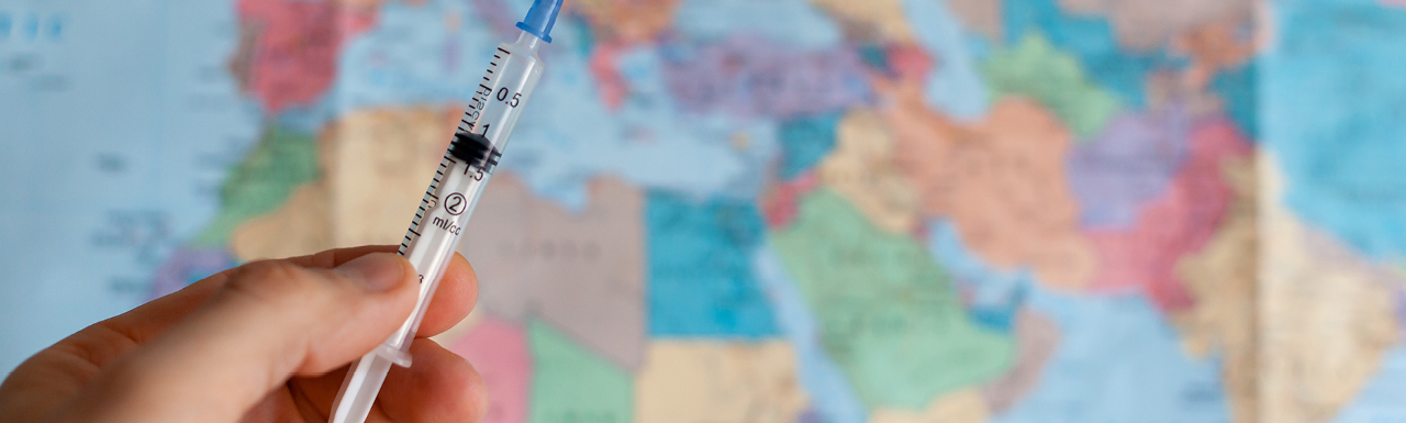 A syringe in front of a world map A syringe in front of a world map