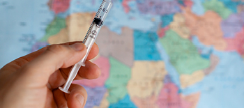 A syringe in front of a world map A syringe in front of a world map