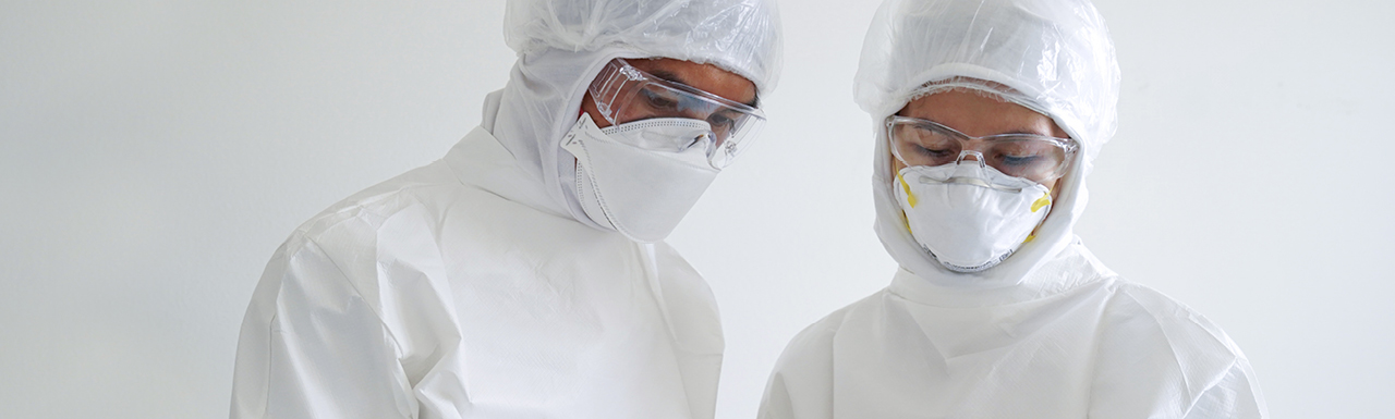 Two researchers working and looking down in their protective gear Two researchers working and looking down in their protective gear