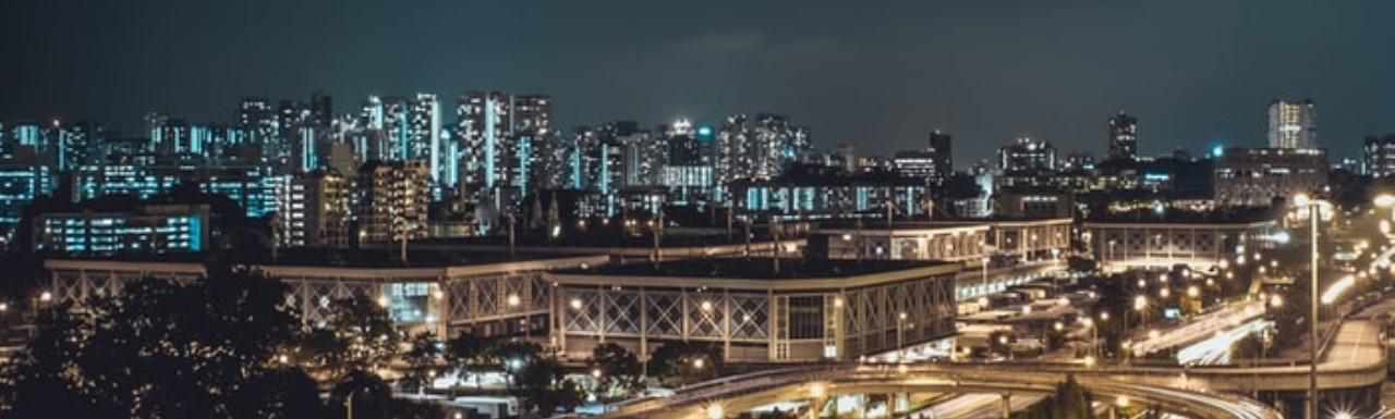 A city in the evening with all buildings lit up and traffic passing through