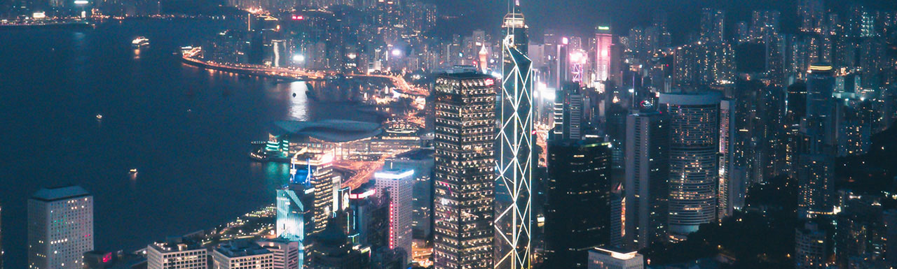 A city in the evening with all buildings lit up and an ocean on one side