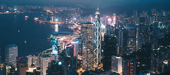 A city in the evening with all buildings lit up and an ocean on one side
