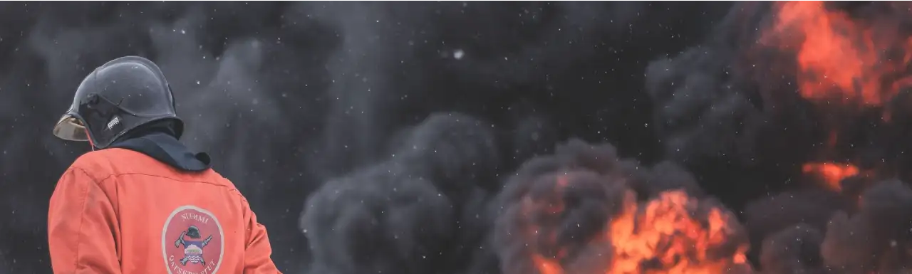 A fire explosion with huge smoke clouds and fire worker looking down A fire explosion with huge smoke clouds and fire worker looking down