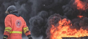 A fire explosion with huge smoke clouds and fire worker looking down