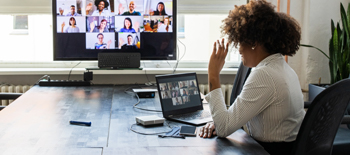 A virtual team call in session with a woman sitting in white and looking at her team mates in screen A virtual team call in session with a woman sitting in white and looking at her team mates in screen