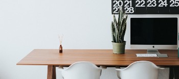 A desk with a computer set up, a plant and a diffuser